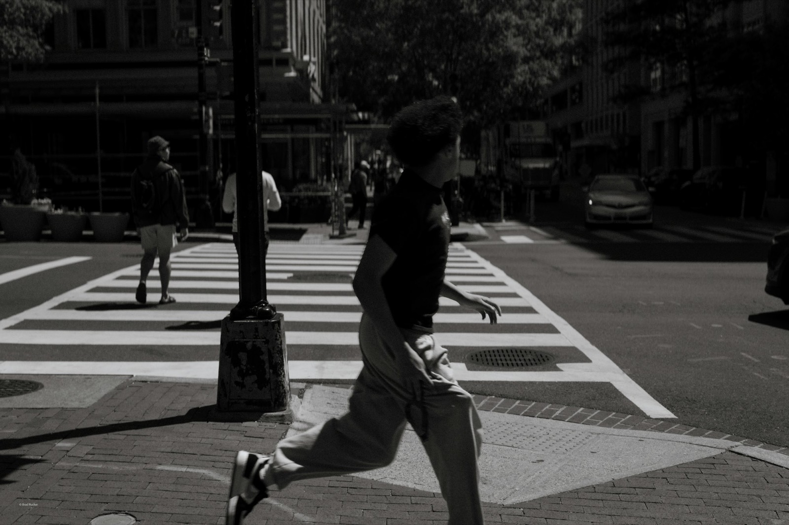 Runner crossing a city street at midday